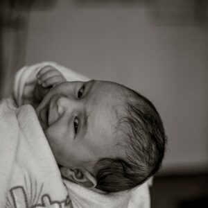 Beautiful black and white portrait of a newborn wrapped in a robe during a baptism ceremony.