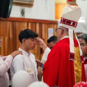 Bishop performing confirmation during a church ceremony with young participants.